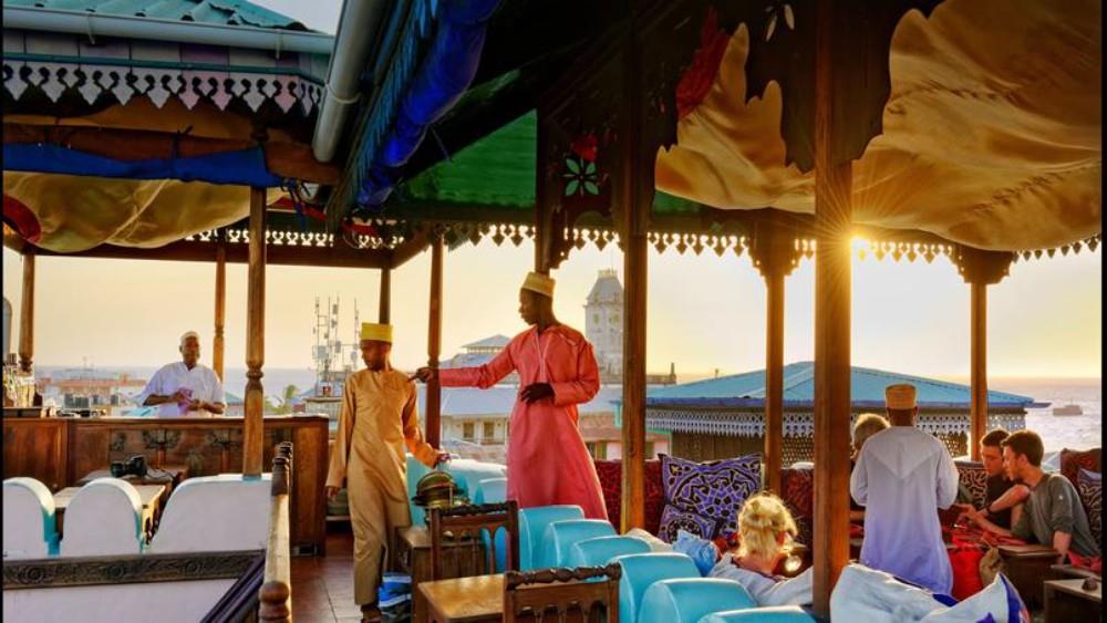Guests on a Stone Town rooftop terrace at sunset