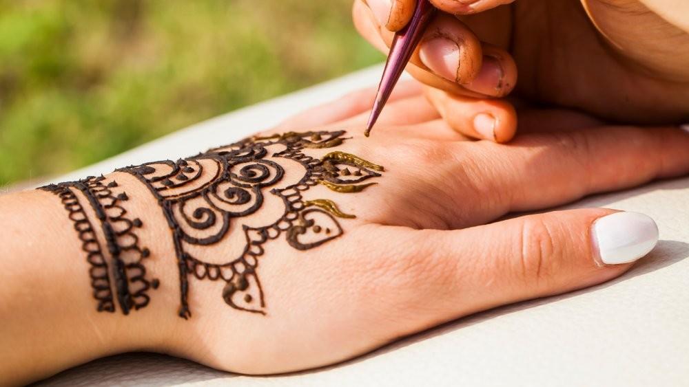 Intricate henna patterns being painted on a hand