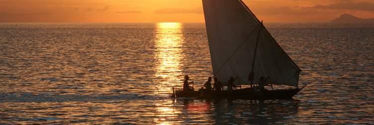 Traditional dhow boat sailing off Zanzibar at sunset